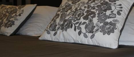 A bed with two pillows featuring a floral pattern.
