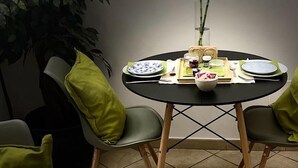 A dining table with two chairs, a vase with a plant, and a tray with food items. - Hotel Trieste Catania (Catania)