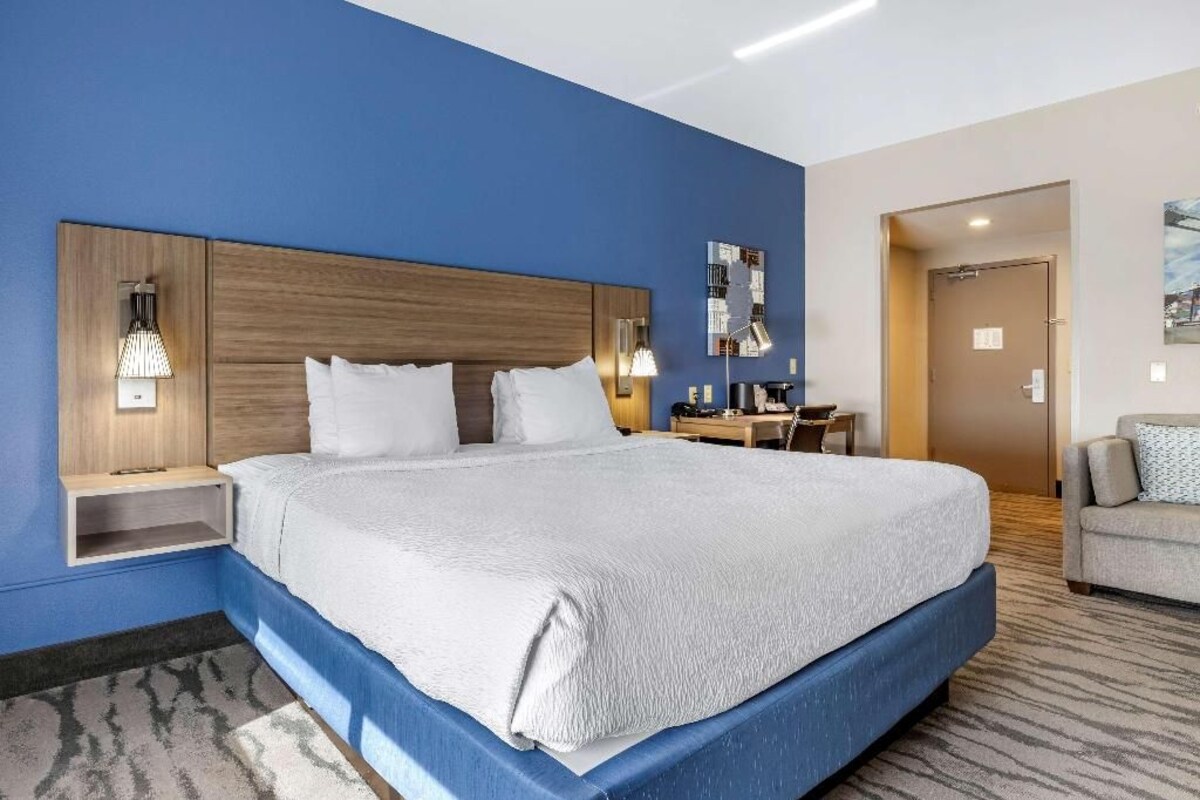 A hotel room with a large bed, bedside tables, a desk, and a chair.