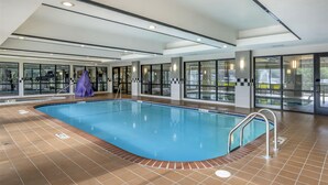 An indoor swimming pool with clear glass walls, a tiled floor, and a covered area. - Best Western Plus Castlerock Inn & Suites (Bentonville)