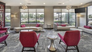 A modern lounge area with sofas, chairs, and a coffee table. Large windows provide a view of the outdoors. - Best Western Plus Castlerock Inn & Suites (Bentonville)