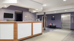 A reception area with a reception desk, a flat-screen TV, a wall-mounted sign, and an elevator. - Microtel Inn & Suites by Wyndham Sault Ste. Marie (Sault Ste. Marie)
