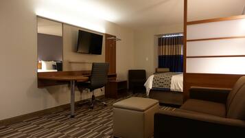Una habitación de hotel con cama, escritorio con silla, televisor y sofá.