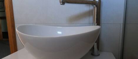 Uma pia de cerâmica branca com uma torneira moderna sobre um balcão branco.