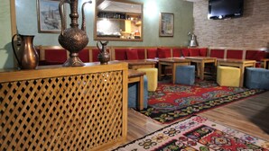 A restaurant with wooden furniture, a patterned carpet, and a television mounted on the wall. - Hotel Pansion Stari Grad - Sarajevo (Sarajevo)