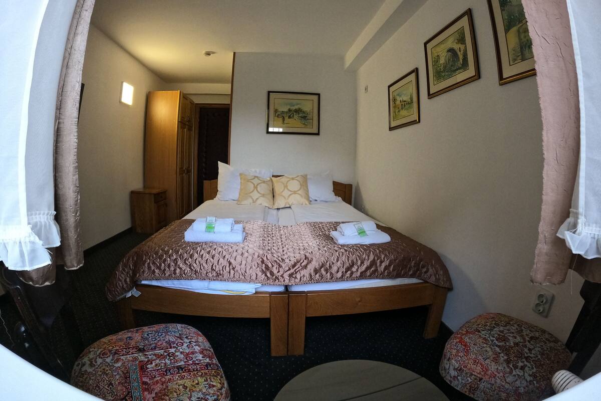 A hotel room with a large bed, two bedside tables, a wardrobe, and a door leading to a bathroom.