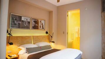 A hotel room with a bed, bedside lamps, a nightstand, and a ceiling fan.