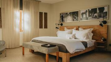 A neatly arranged bedroom with a large bed, a bedside table, a bench, and a chair.