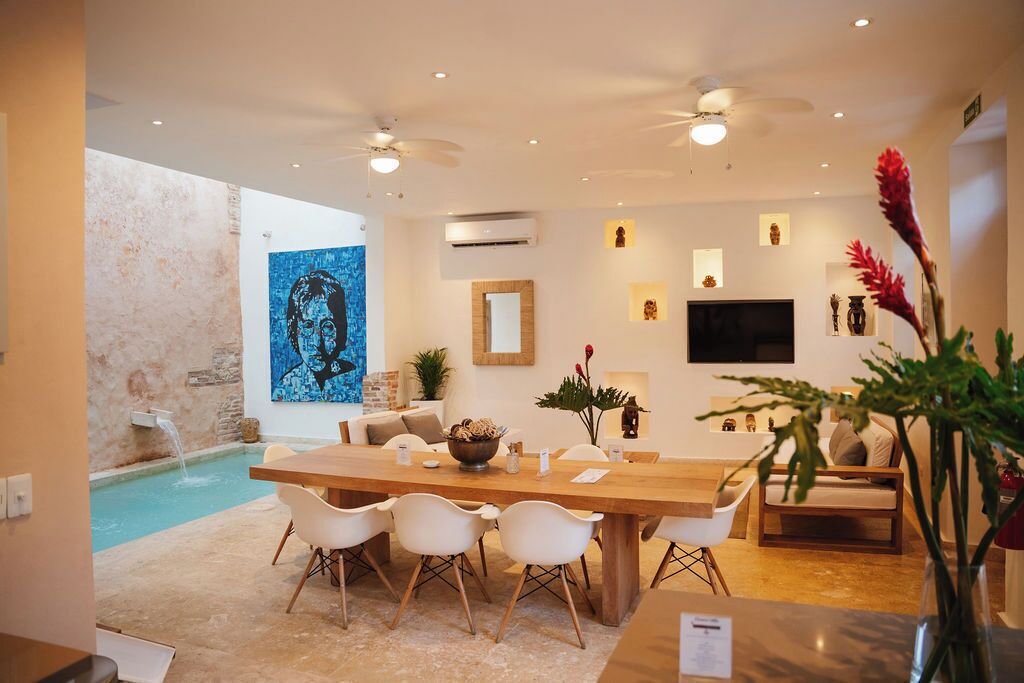 A modern living room with a dining area, a pool, and a large artwork on the wall.