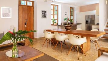 A modern kitchen with a wooden dining table, white chairs, and a refrigerator.