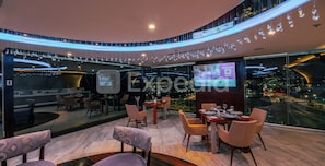 A modern restaurant with a panoramic city view, a digital screen, and a ceiling adorned with hanging crystal lights. - HS HOTSSON Hotel Querétaro (Querétaro)