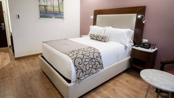 Un dormitorio ordenado con cama, mesita de noche y una pequeña mesa redonda.