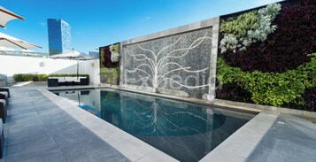 Una piscina al aire libre, sombrillas, sillones reclinables de piscina