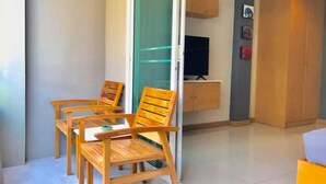 Ein modernes Wohnzimmer mit Glastür zum Balkon, Holzmöbel, einem Flachbildfernseher und Einbauschränken.