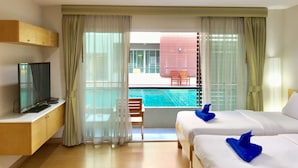 Ein Hotelzimmer mit zwei Betten, einem Fernseher und Blick auf einen Swimmingpool.