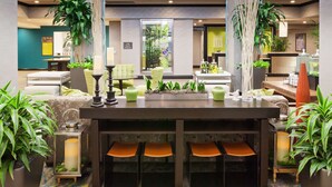 Un hall d’entrée moderne avec un comptoir d’accueil, un espace salon et des plantes en pot.