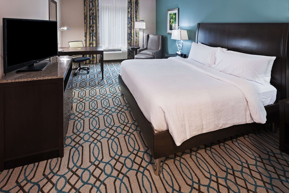 A hotel room with a bed, a desk, a television, and a chair.