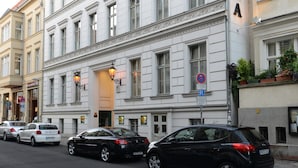 En byggnad med flera våningar i en klassisk arkitektonisk stil, med en framträdande entré och en skylt som visar texten "ALLEGRA".