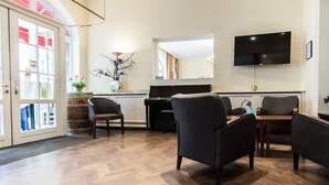 Ett modernt vardagsrum med ett piano, bekväma sittmöbler, en platt-TV och ett stort fönster med utsikt.