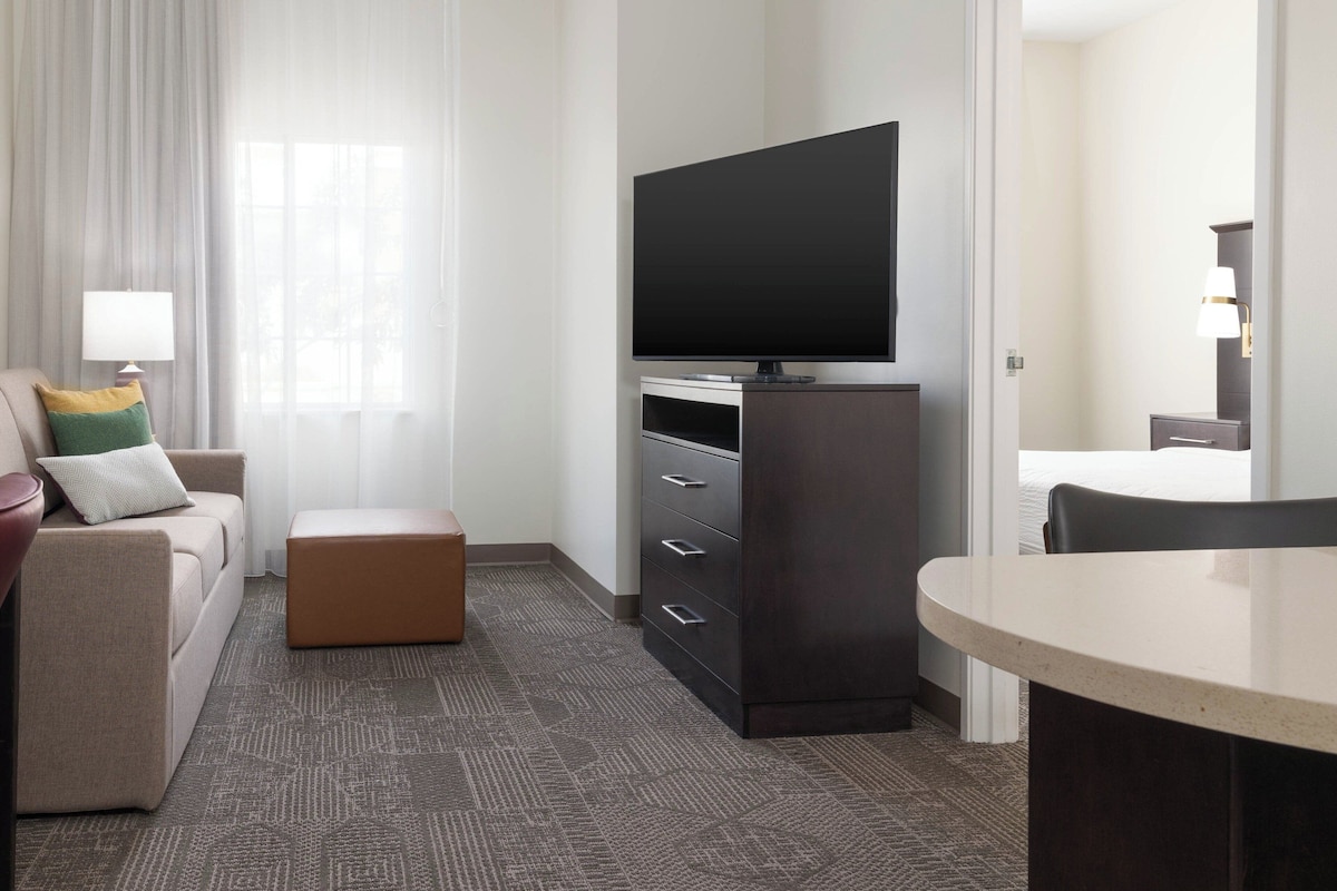 Een hotelkamer met een flatscreen televisie, een bank, een salontafel, een bureau en een stoel.