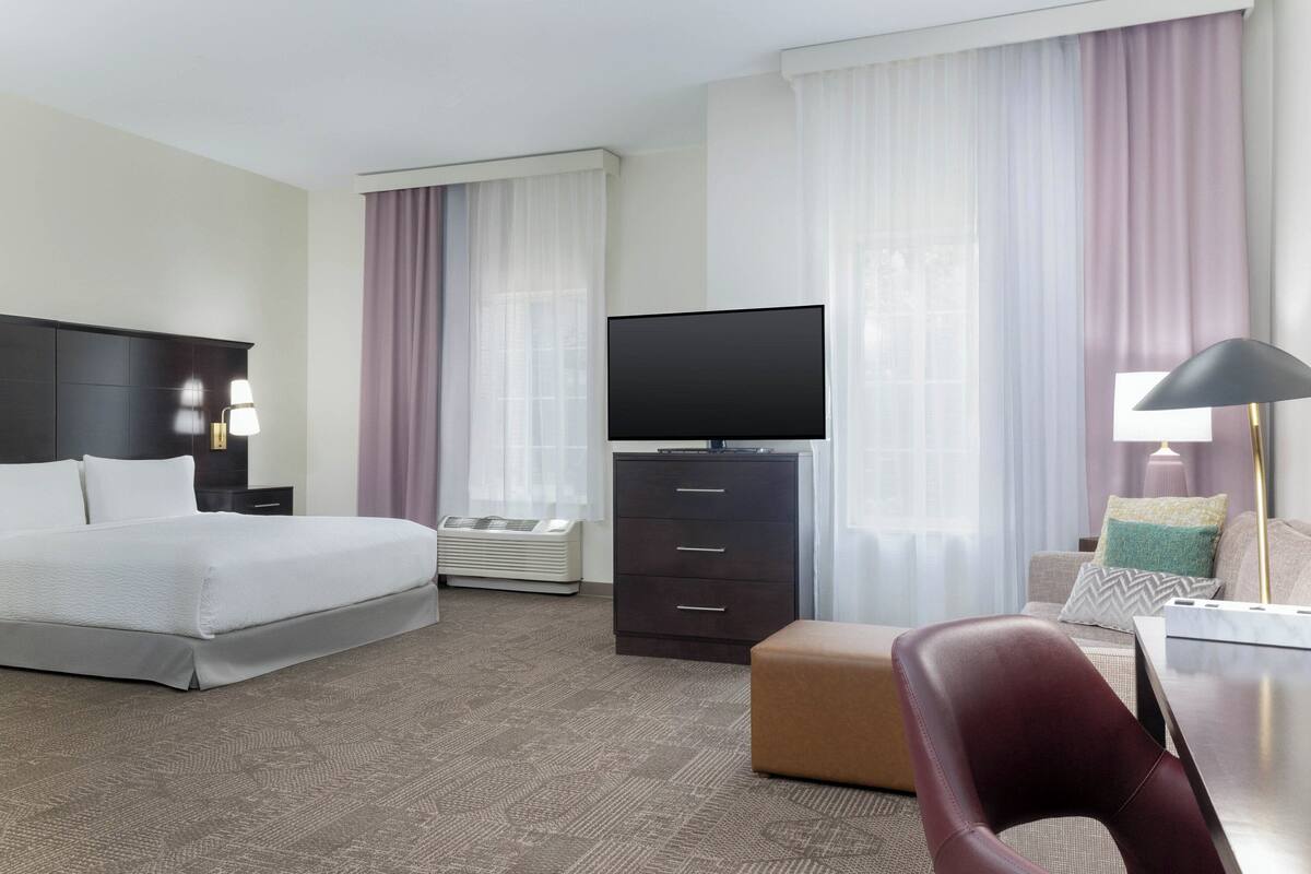 Une chambre d’hôtel équipée d’un lit, d’un téléviseur à écran plat, d’une commode, d’un bureau et d’une chaise.