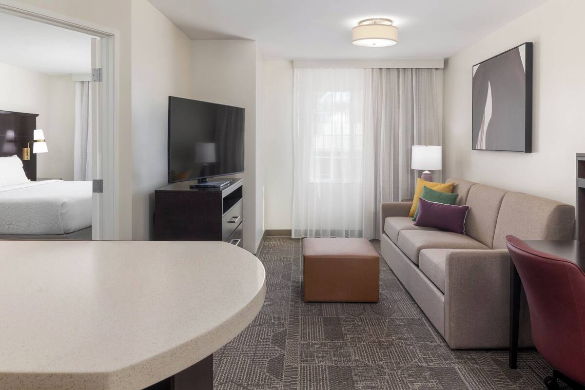 Une chambre d’hôtel moderne équipée d’un lit, d’une télévision, d’un canapé, d’une table basse et d’une table à manger.
