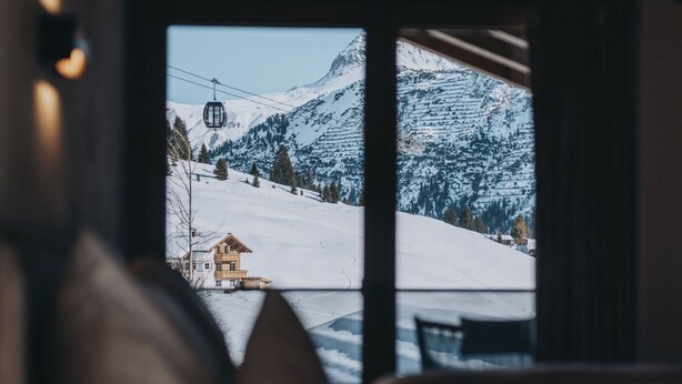 Una habitación acogedora con vista a una montaña nevada y una cabaña.