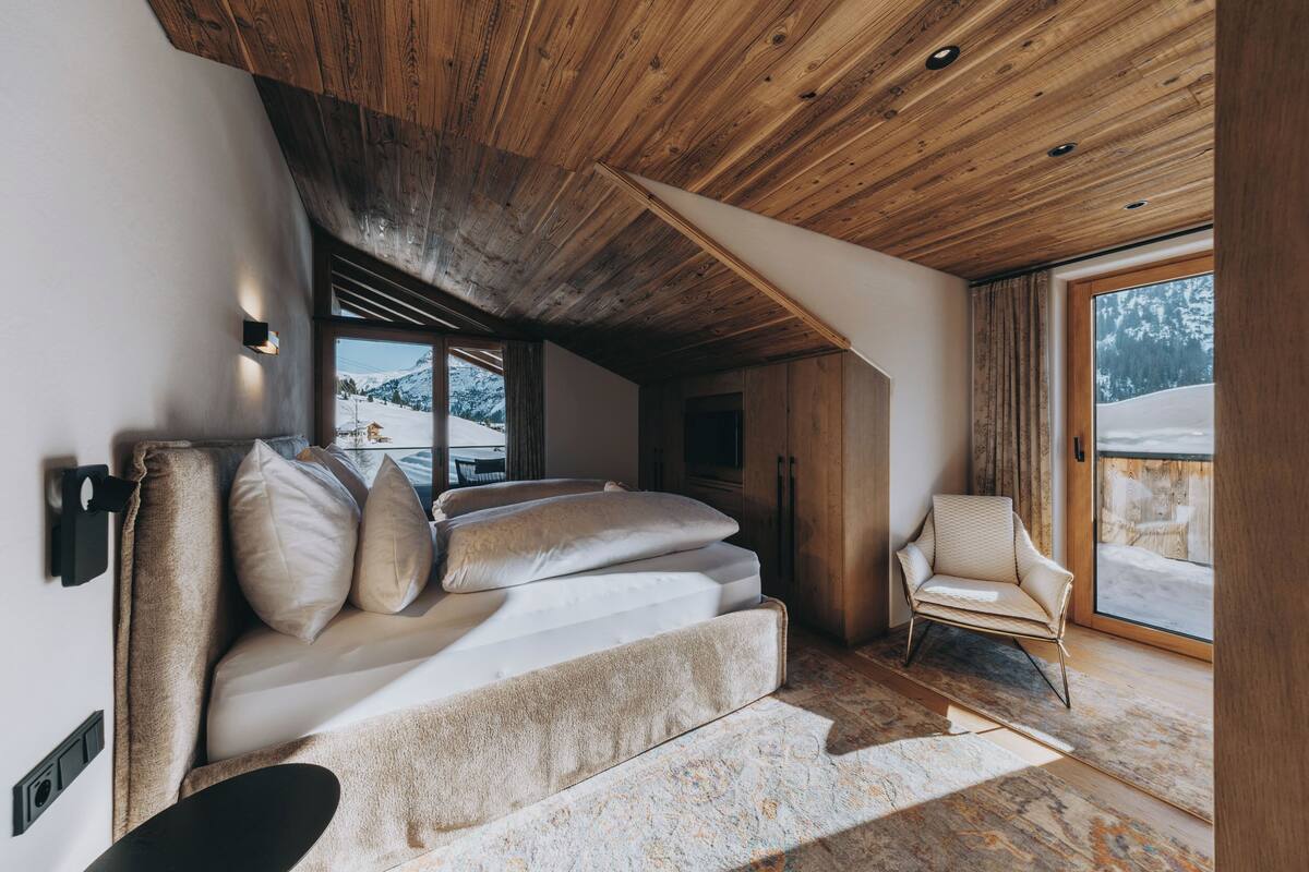 A cozy room with a sofa, a chair, and a large window offering a view of a snowy landscape.