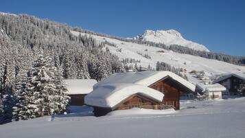 A snow-covered mountain with wooden cabins and a clear blue sky.