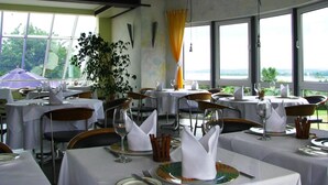 A restaurant with multiple tables set for dining, featuring white tablecloths and neatly arranged cutlery. - Hotel Sonnenhaken (Buschvitz)