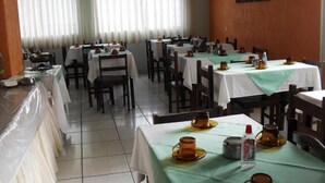 A dining area with multiple tables, chairs, and a tiled floor. - Hotel Fátima (Divinopolis)