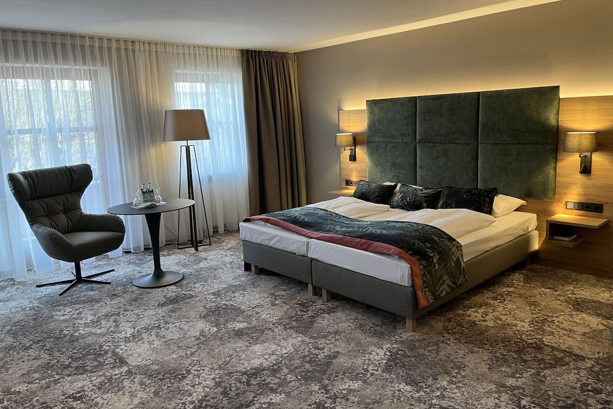 Une chambre d’hôtel avec un grand lit, une chaise, une petite table et une lampe.