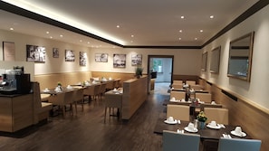 Un espace repas moderne avec un plancher en bois, des banquettes beiges et des tables dressées pour le service.