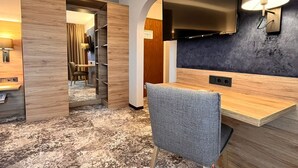 Une chambre d’hôtel équipée d’un bureau, d’une chaise, d’une télévision et d’une lampe fixée au mur.