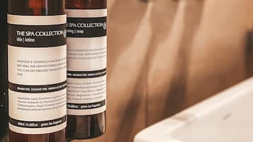 Zwei Flaschen der Spa Collection mit Haut- und Körperlotion hängen im Badezimmer an einer Wand.
