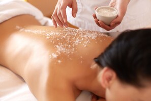A person receiving a massage with salt being applied to their back. - Villa de Duinen (Noordwijk)