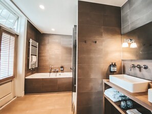 A modern bathroom with a bathtub, a shower, and a vanity with a sink. - Villa de Duinen (Noordwijk)