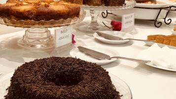A dessert display with various cakes and pastries on glass stands, labeled with names.