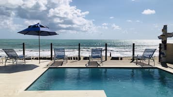 Una piscina al aire libre, sombrillas, sillones reclinables de piscina