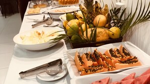 Una mesa de buffet con diversas frutas, como sandía, papaya y plátanos, así como una variedad de platos.