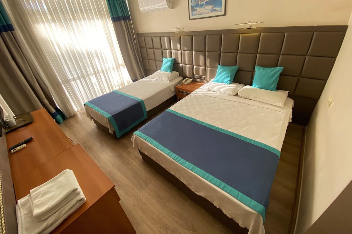 Habitación de hotel con dos camas, un escritorio de madera, un teléfono y un cuadro en la pared.