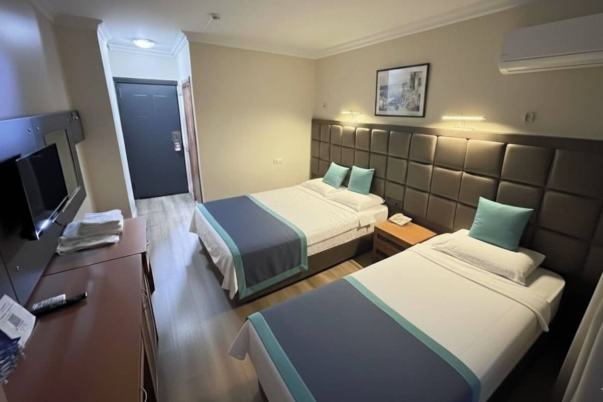 Habitación de hotel con dos camas, un escritorio, un televisor y una puerta.
