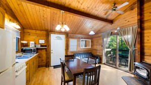 L’intérieur d’un chalet en bois comprend une cuisine, un coin repas et une porte-fenêtre coulissante donnant sur l’extérieur.