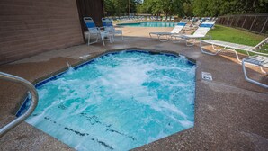 Un espace avec un jacuzzi, une piscine, des chaises longues et un mur en briques.