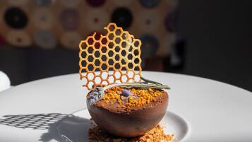 A dessert on a white plate with a honeycomb structure on top, placed on a table with a polka-dotted cloth in the background.