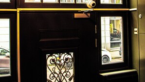 Une pièce dotée d’un grand lustre sphérique, d’une porte en fer forgé décorative et de nombreuses fenêtres.