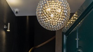 Un escalier agrémenté d’un luminaire décoratif et d’une porte verte dotée d’une poignée ornée.