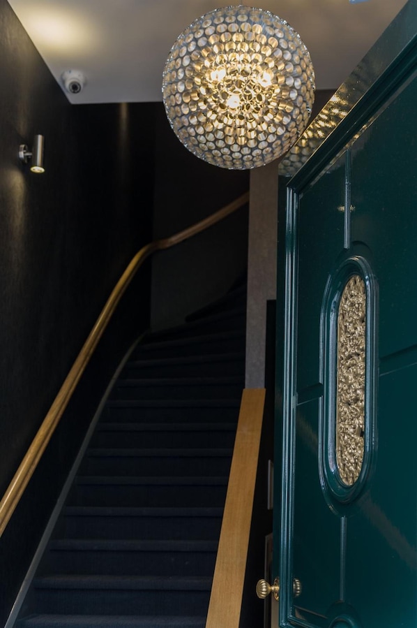 En trappa med en dekorativ lampa och en grön dörr med ett utsmyckat handtag.