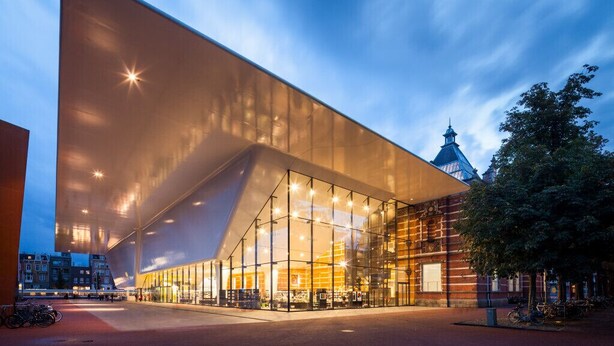 Un bâtiment moderne doté d’une grande façade en verre et d’une corniche saillante.