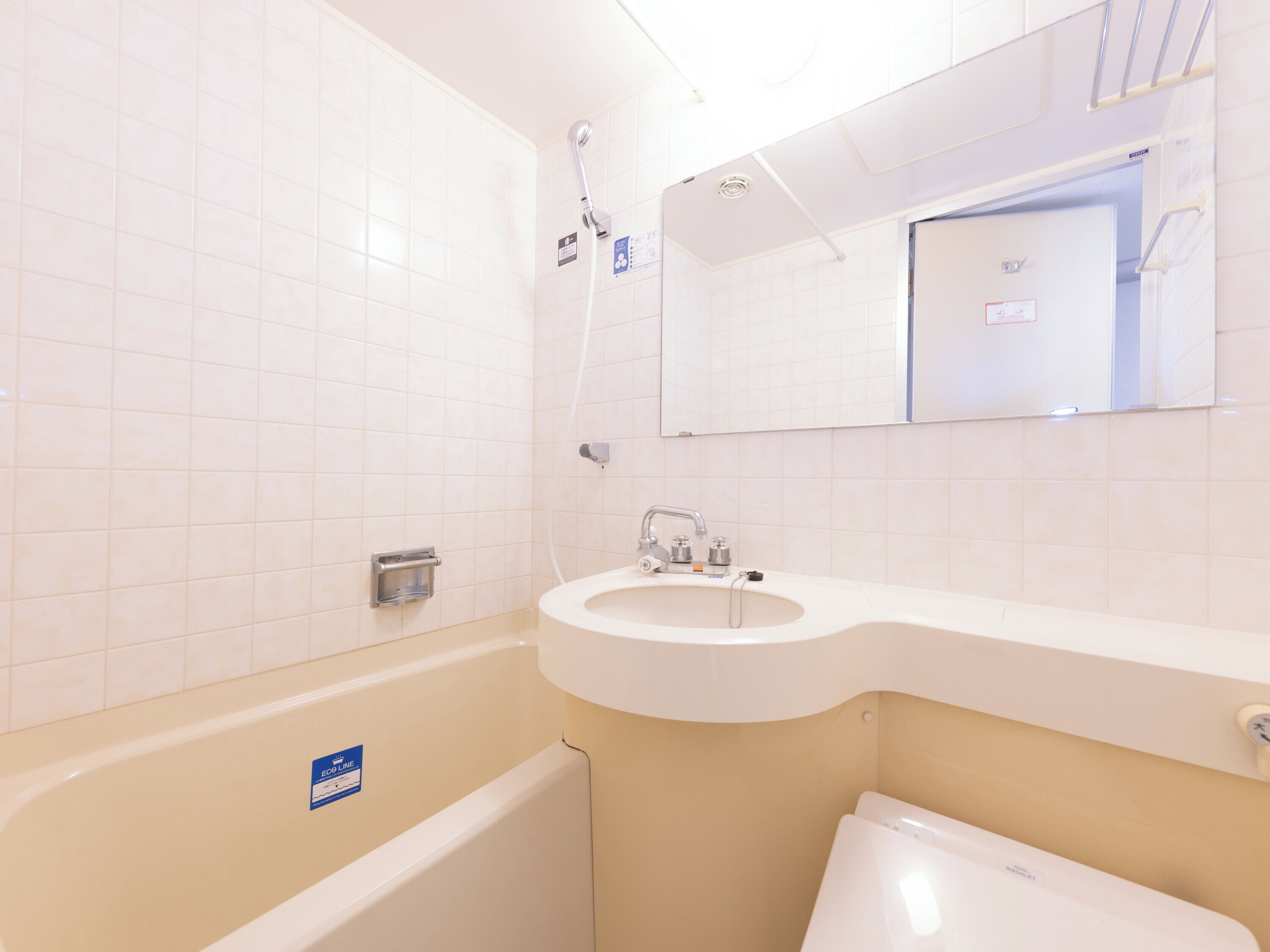 A bathroom with white tiles, a bathtub, a sink, and a toilet.